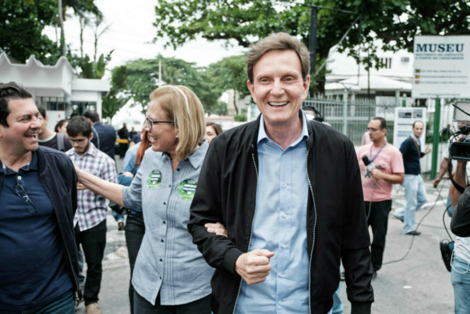 Rio de Janeiro's mayoral candidate for the Brazilian Republican Party (PRB) Marcelo Crivella walks with his wife Sylvia Jane (C) after casting his vote at a polling station during the municipal election runoff in Rio de Janeiro, Brazil, on October 30, 2016. An evangelical mega-church bishop who once branded Catholics demons was expected to become mayor of Rio de Janeiro on Sunday in nationwide municipal elections confirming Brazil's shift to the right. / AFP PHOTO / YASUYOSHI CHIBA