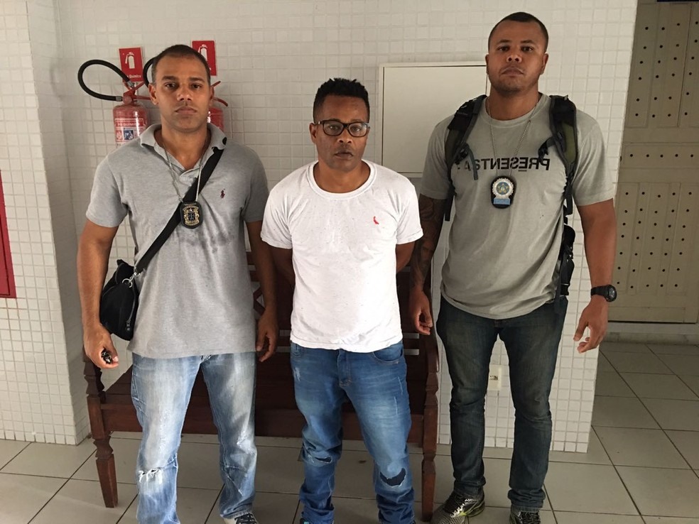 CrÃ¢nio entre dois policiais apÃ³s ser preso em Salvador (Foto: DivulgaÃ§Ã£o/ PolÃ­cia Civil)