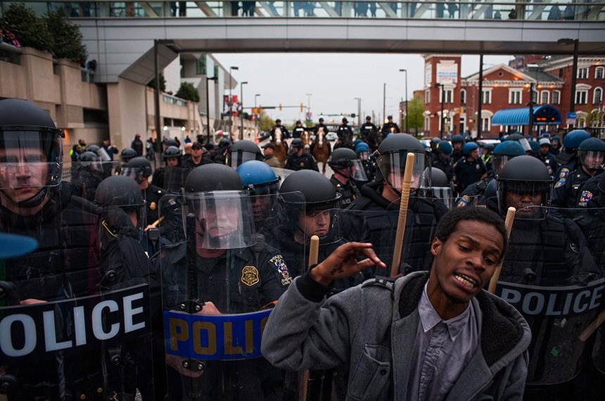 epa04720846 A protestor reacts as he stands in front of police officers during a demonstration outside of Camden Yards to protest the death of Freddie Gray in Baltimore, Maryland, USA, 25 April 2015. Gray died of spinal cord injuries on 19 April while in police custody; the US Justice Department announced that they are launching their own investigation into the case.  EPA/NOAH SCIALOM