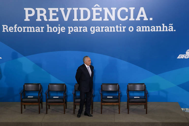 O presidente Michel Temer no palco com cadeiras e ao fundo o cartaz "Previdência. Reformar hoje para garantir o amanhã"