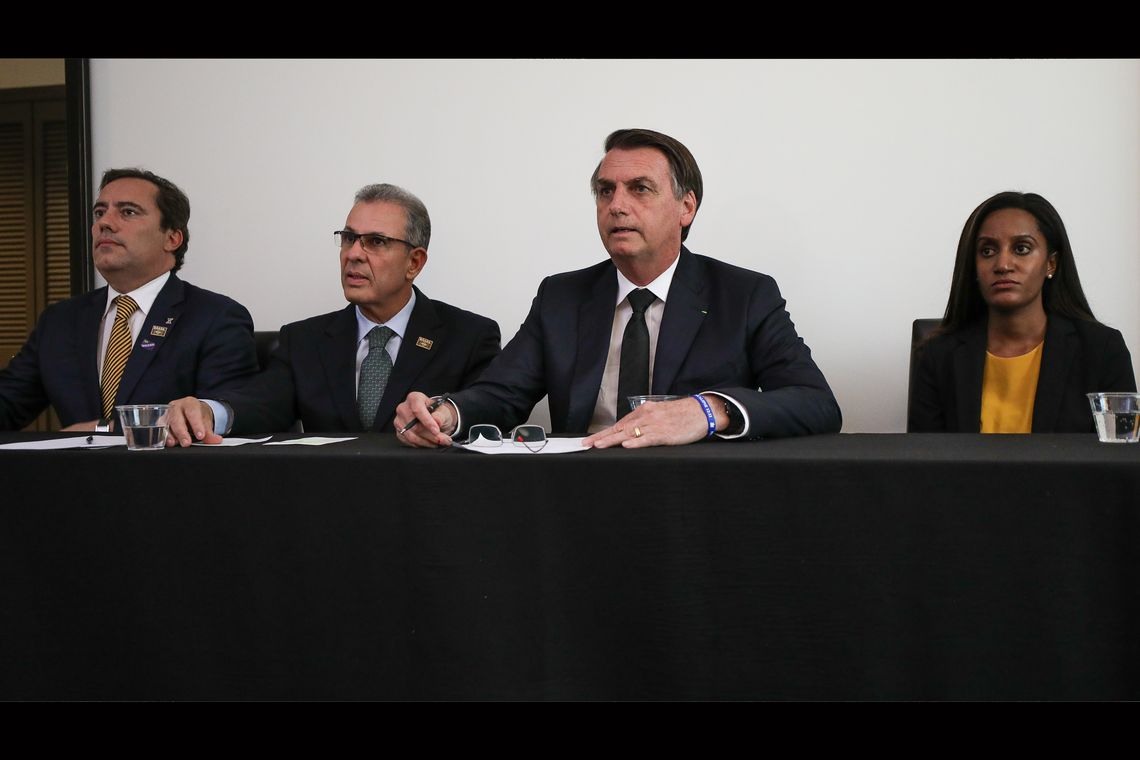 O presidente Jair Bolsonaro, em Dallas (EUA), faz transmissÃ£o ao vivo para as redes sociais. ao lado do presidente da Caixa, Pedro GuimarÃ£es, do ministro de Minas e Energia, Bento Albuquerque, e da intÃ©rprete de libras, Joyce Porto.