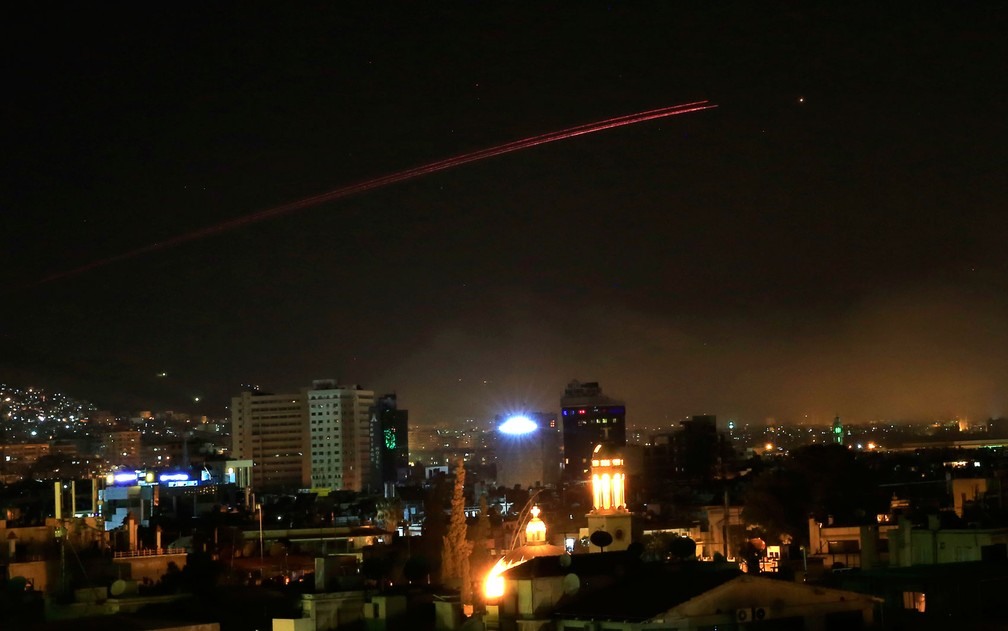  Fogo anti-aÃ©reo ilumina o cÃ©u de Damasco em resposta ao ataque dos EUA, Reino Unido e FranÃ§a Ã  capital da SÃ­ria na madrugada de sÃ¡bado (14)  (Foto: Hassan Ammar / AP Photo)