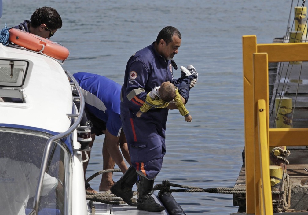 Socorrista do Samu leva um bebê no colo após uma embarcação naufragar em Mar Grande, na Baía de Todos os Santos, na Bahia (Foto: Xando Pereira/Agência A Tarde/Estadão Conteúdo)