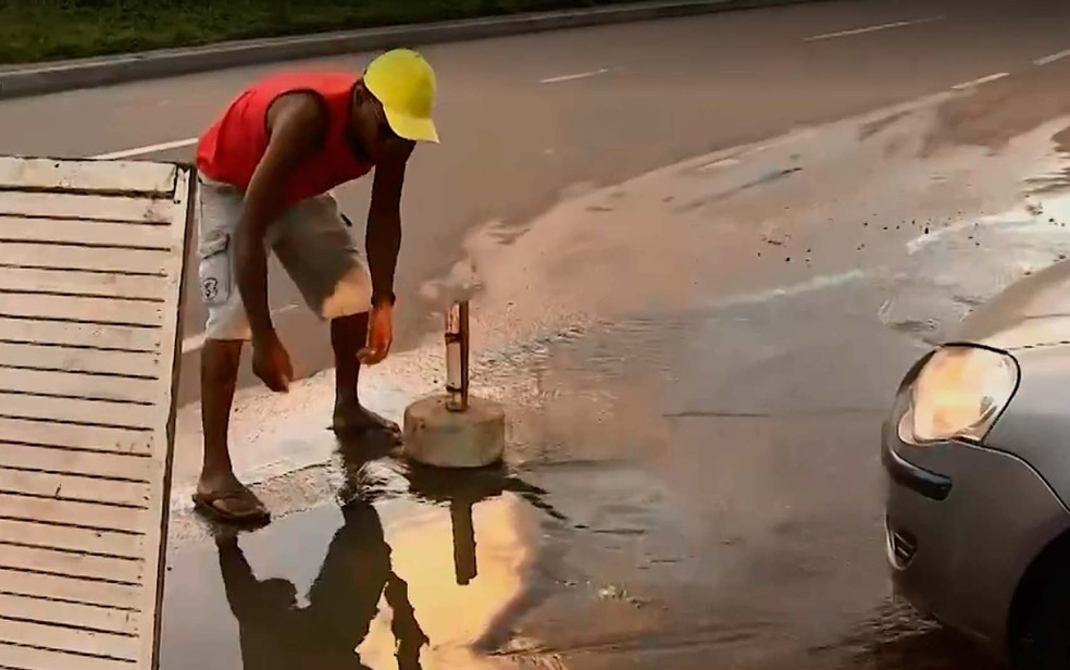 Vazamento de Ã¡gua na Estrada da Rainha e morador sinalizando ponto de saÃ­da da Ã¡gua em Salvador (Foto: ReproduÃ§Ã£o/TV Bahia)