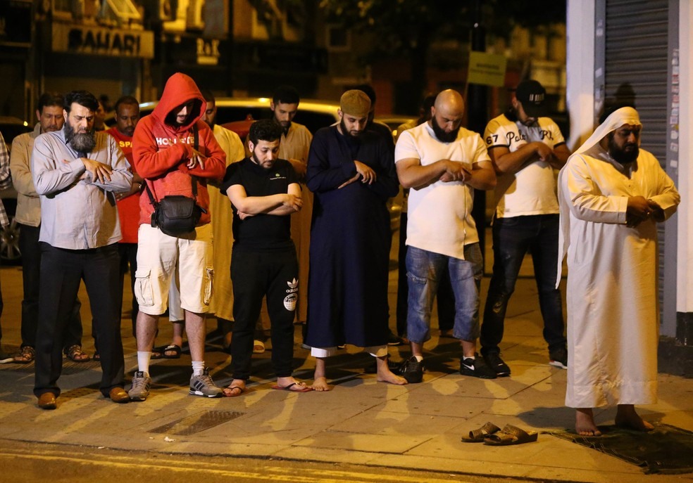 Homens oram após motorista atropelar pessoas em frente a mesquita em Finsbury Park, no norte de Londres (Foto: Neil Hall/Reuters)