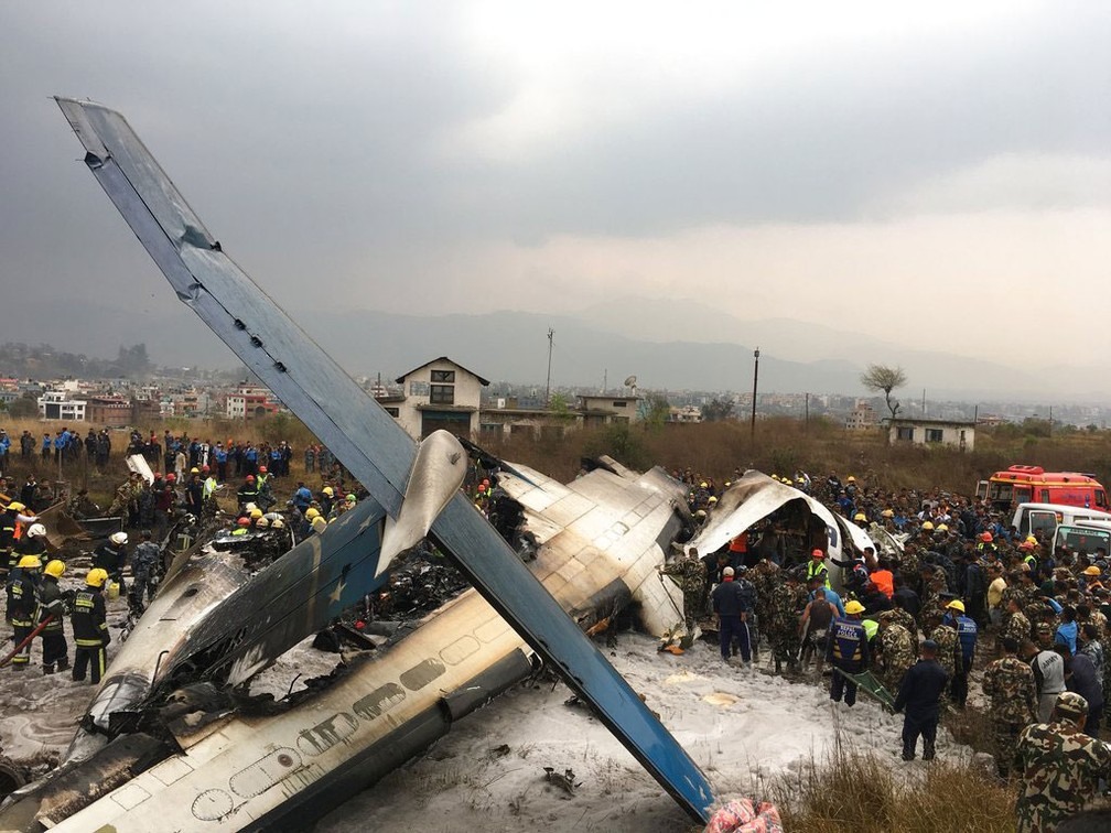 Equipes de resgate trabalham após avião cair no aeroporto de Katmandu, no Nepal, na manhã desta segunda-feira (12)  (Foto: Niranjan Shreshta/ AP)